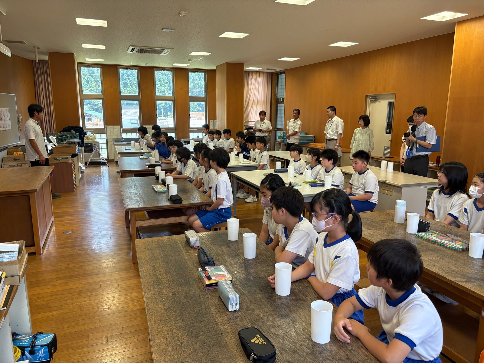 白いカップを前に制作の説明を聞く美山小学校の児童たち