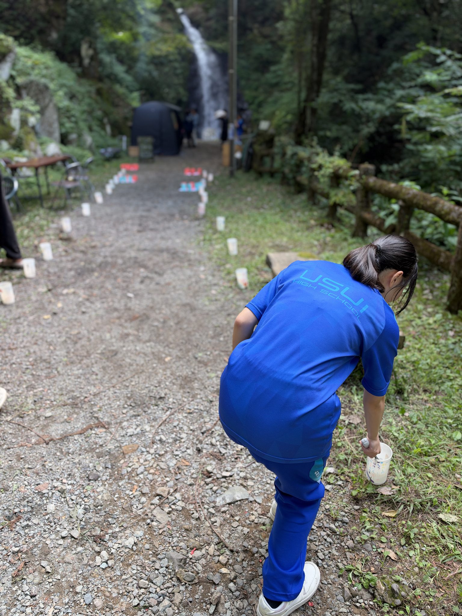 滝までの道に沿ってカップを並べる羽水高校の生徒。奥の黒いテントがサウナです。